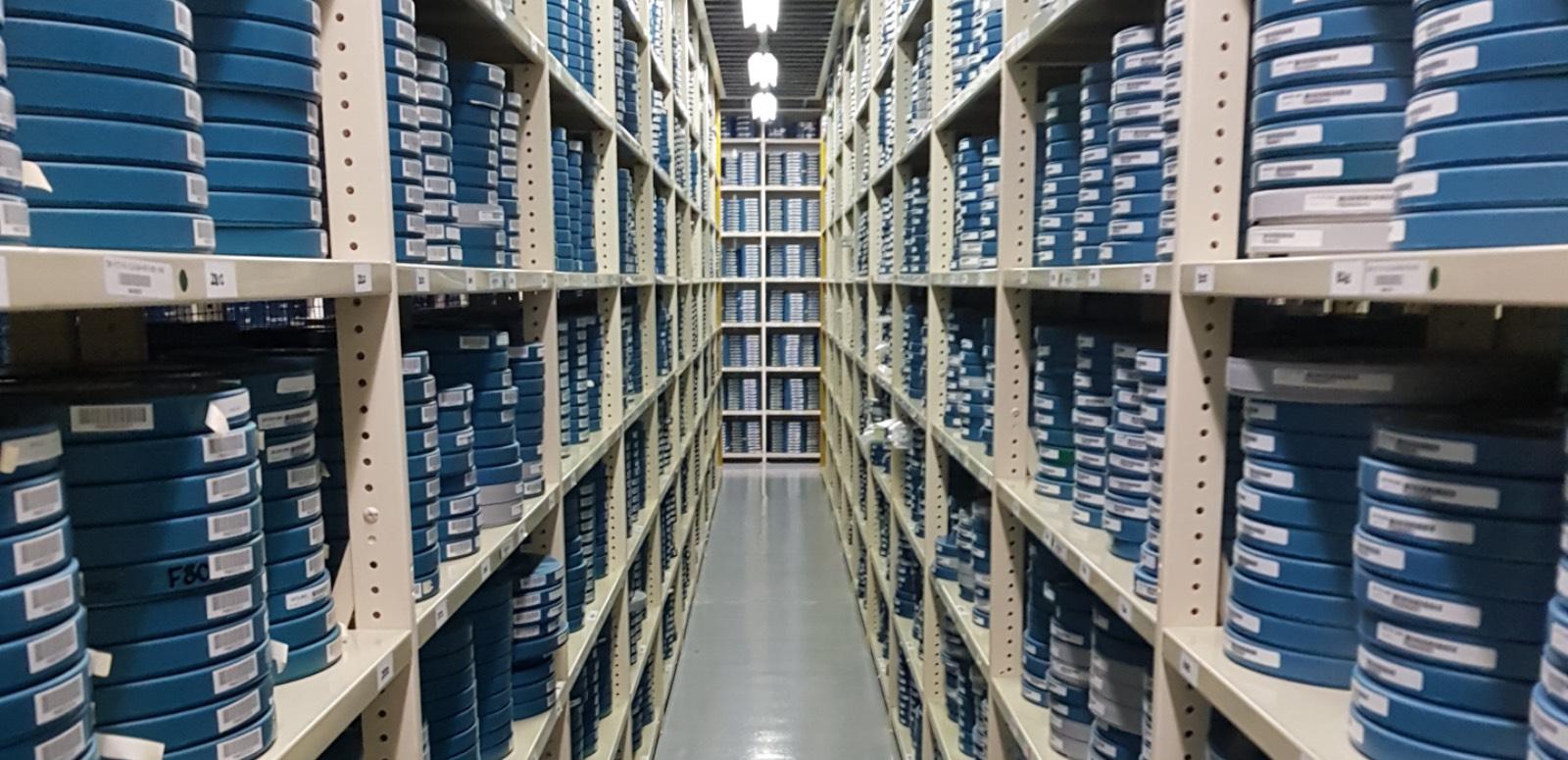 Rows of shelving stacked with film canisters in the NFSA vaults