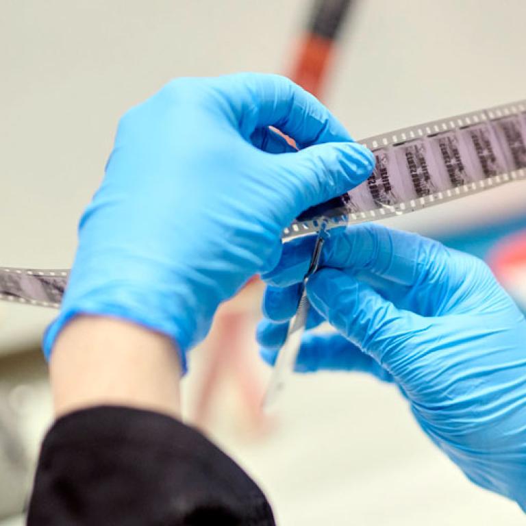 A pair of hands wearing blue rubber gloves and making a heart shape with their fingers and thumbs.